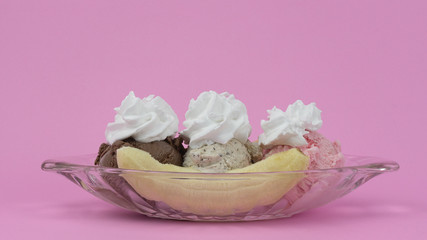 Fototapeta na wymiar Ice cream Banana Split in glass topped whip cream on pink background, Food concept, Blank for design..