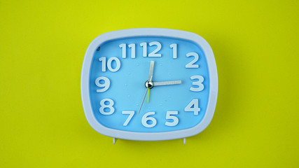 Blue Alarm clock face beginning of time 12.14 on Yellow background, Copy space for your text, Time concept..