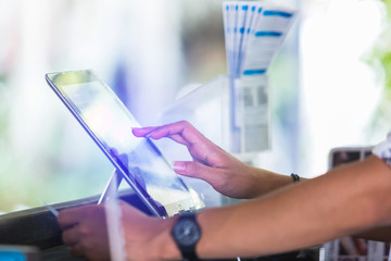 Cashier staff using tablet to receive orders from customers at counter service in cafe or store. Cashier takes payment from customer with digital tablet.