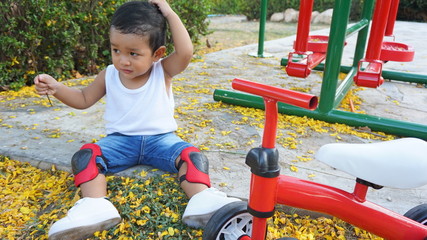 Cute little boy sitting in summer park. Creative child happy on nature. Outdoors activity for toddler kid. Talented baby boy from Asian Thailand. 