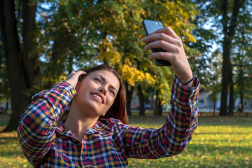 Selfie time. Beautiful young girl taking a selfie at the park.