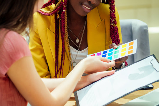 african american business female with pigtails dreadlocks wearing yellow jacket discussing with partners in office and choosing palette of colors of advertising