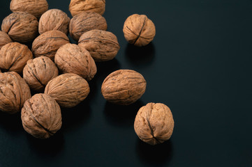 Pile of walnuts on black background. Side view.