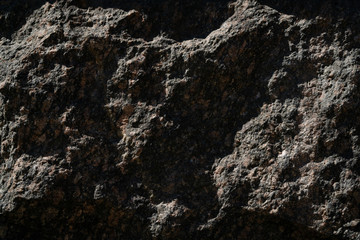 Stone wall background dark. Large relief stone blocks on the wall. Game of shadows and lights on a massive dark wall.