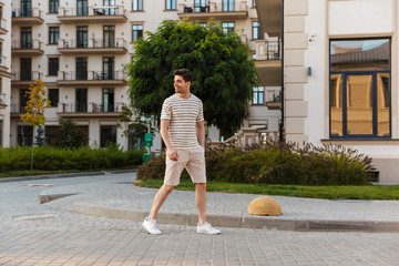Image of man smiling and holding hand in his pocket while walking