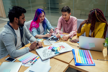 creative agency designer team working together:african american woman with dreadlocks pigtails and caucasian girl pink blue multi-colored hair communication with indian man in office