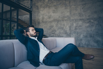 Profile photo of handsome stylish trendy business person guy sitting minded hands behind head on sofa in trendy design apartments office loft building indoors wear formalwear costume