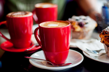 Red coffee cups with coffee and delisious berry muffin for breakfast at the cafe