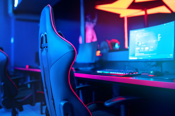 Blurred background computer pc, keyboard armchair, blue and red lights. Concept online eSports arena for gamer playing tournaments - obrazy, fototapety, plakaty