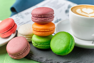 Closeup of several colored french pasta cakes, cup of cappuccino