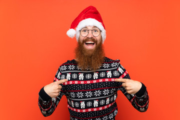 Christmas man with long beard over isolated red background with surprise facial expression