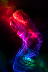 Obraz premium Conceptual avant-garde portrait of a beautiful young girl covered with multicolored lines applied by a light brush. Art style creative photo. Advertising, fashion and commercial design.