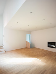 Empty white room with rough parquet, fireplace and spotlights
