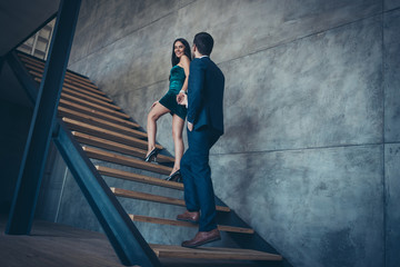 Full length rear view photo of tender trendy couple guy lady erotic desire climbing up second floor holding hands new house excursion wear formalwear suit short dress loft indoors