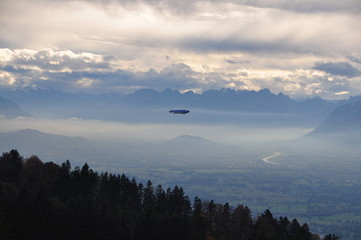 a zeppelin airship flying over the Alps seen from the Pfänder, Voralberg, Austria © Simo