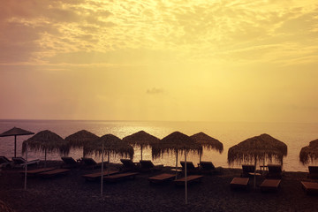 Sunrise in popular volcanic beach of Perissa with dark sandy seascape, Santorini island, Cyclades, Greece