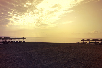 Sunrise in popular volcanic beach of Perissa with dark sandy seascape, Santorini island, Cyclades, Greece