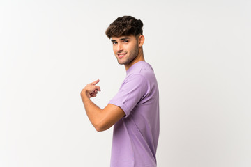 Young handsome man over isolated white background pointing back