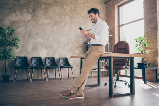 Full body profile side photo of confident smart middle eastern joyful businessman using smartphone send message to work colleagues partners feel content wear style pants trousers in loft office