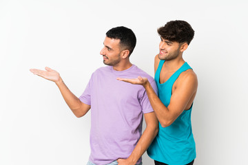 Fototapeta premium Two men over isolated background pointing back and presenting a product