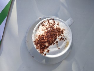 cup of coffee with cream on wooden background