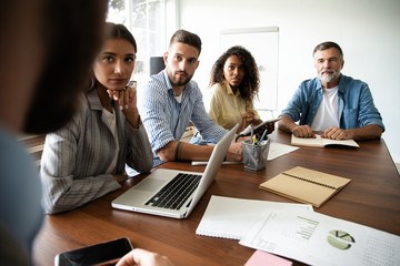 Group of young business people working and communicating while sitting at the office desk together