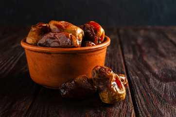 Clay brown bowl with dried dates on a wooden table. Healthy sweets, healthy nutrition.
