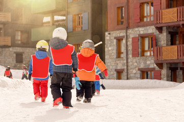 Group of young kids walking back to the ski resort village after ski lessons, the Alps France