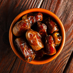 Clay brown bowl with dried dates on a wooden table. Healthy sweets, healthy nutrition. Traditional dessert in ramadan.