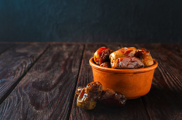 Clay brown bowl with dried dates on a wooden table. Healthy sweets, healthy nutrition.