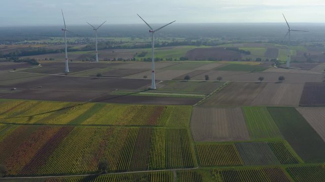 Aerial view of wind turbines beside vineyards in Germany. On a sunny day in Autumn, fall. Zoom out from the turbines.