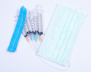 Surgical glove, mask, cap and syringe on white background. Medical equipment used for surgery.