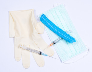 Surgical glove, mask, cap and syringe on white background. Medical equipment used for surgery.