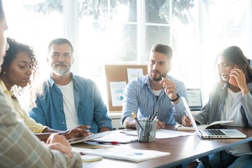 Group of young business people working and communicating while sitting at the office desk together