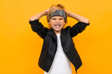upset boy bully rips his hair, a boy in a black jacket on an orange background