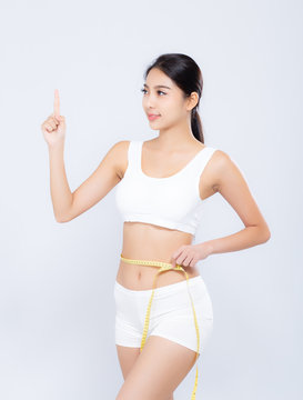 Beautiful asian woman diet and slim with measuring waist for weight finger pointing something isolated on white background, girl have cellulite loss with tape measure, health and wellness concept.