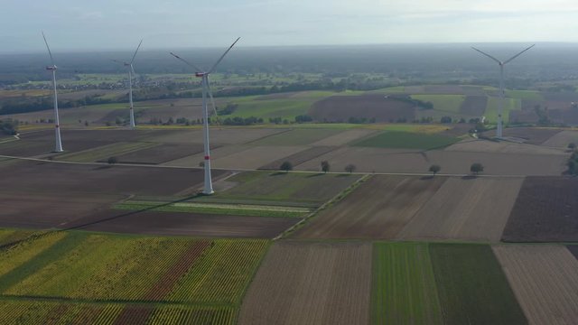 Aerial view of wind turbines beside vineyards in Germany. On a sunny day in Autumn, fall. Pan to the left beside the turbines.