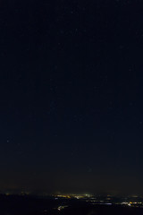 Fototapeta na wymiar Night sky full of stars with distant city, long exposure, Austria landscape