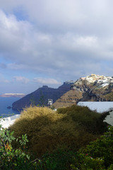 Picturesque and beautiful village of Fira overlooking the caldera with beautiful clouds and blue sky, Santorini island, Cyclades, Greece