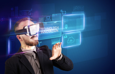 Obraz premium Businessman looking through Virtual Reality glasses with TECHNOLOGY INNOVATION inscription, new technology concept