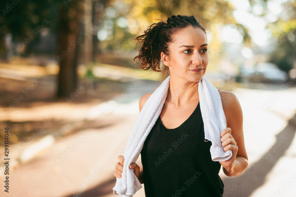 Wall mural Young woman working out. Beautiful woman with towel on athletic track.