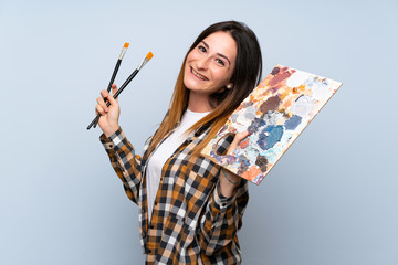 Young painter woman over isolated blue background