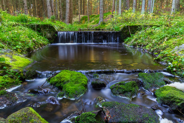 Small weir on brook in forest, long exposure photography, Czech landscape