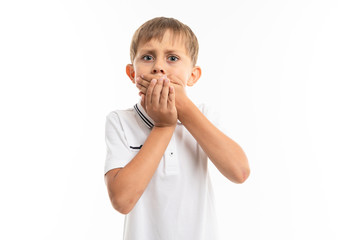 schoolboy on a white background closes his mouth with his hands, is afraid to blurt out, emotional...