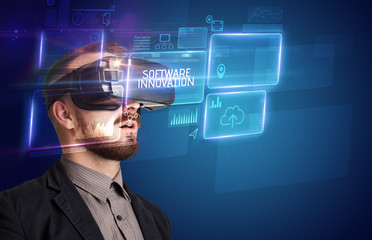 Businessman looking through Virtual Reality glasses with SOFTWARE INNOVATION inscription, new technology concept