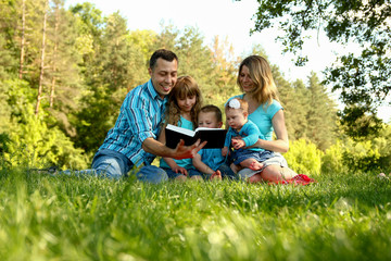 Naklejka na ściany i meble happy family reading the Bible in nature