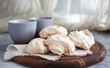Fototapeta na wymiar Homemade white meringue cookies on linen textile. Selective focus. Morning light. Beautiful dessert or breakfast.