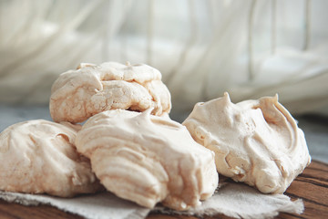 Fototapeta na wymiar Homemade white meringue cookies on linen textile. Selective focus. Morning light. Beautiful dessert or breakfast.