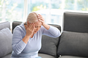 Mature woman suffering from headache at home