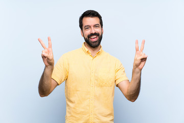 Naklejka premium Young man with beard over isolated blue background showing victory sign with both hands